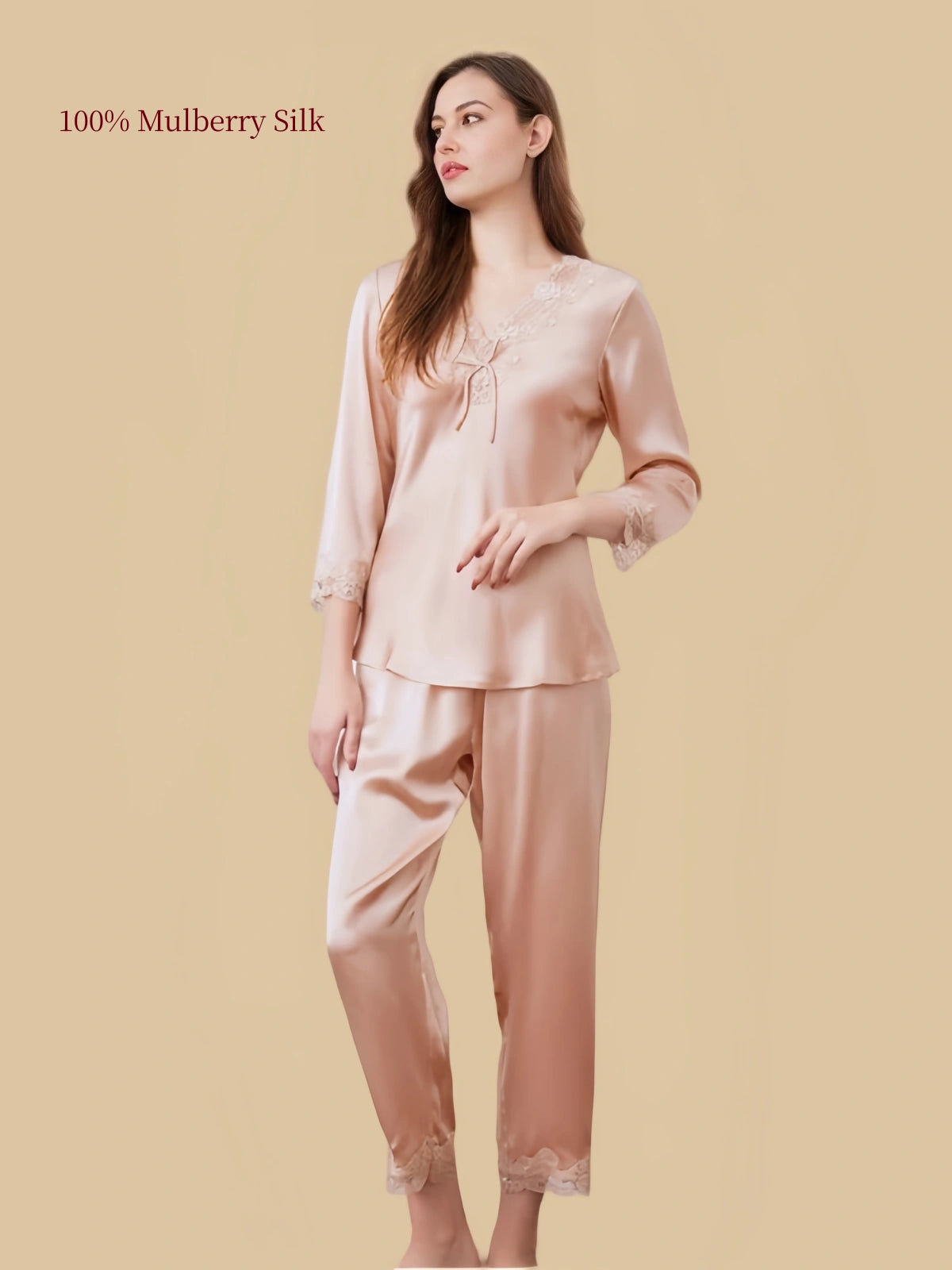 Three-quarter front view of Silkgala Dusty Apricot silk pajamas with a decorative bow neckline, floral lace cuffs and straight-leg pants.