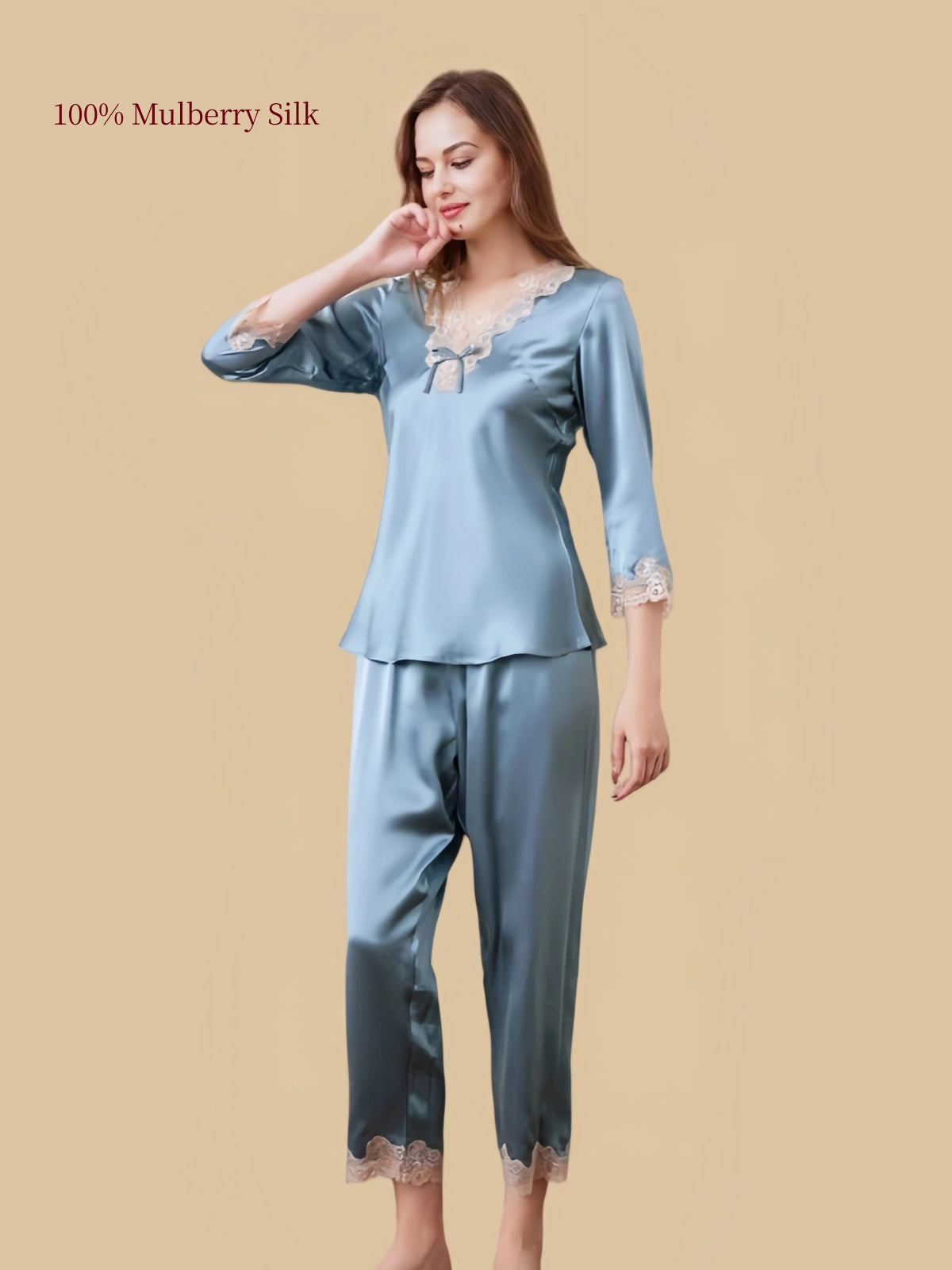 Three-quarter front view of Silkgala Hazy Blue silk pajamas featuring the lace-trimmed V-neck, delicate bow and matching straight-leg pants.