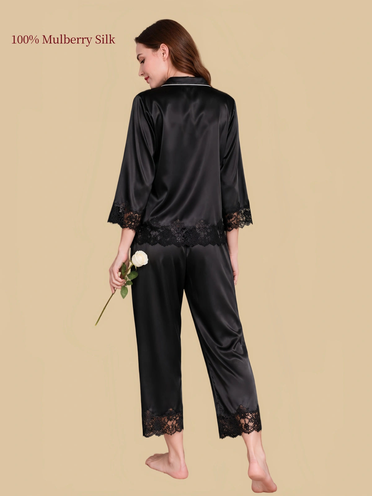 Back view of Silkgala black silk pajamas highlighting black floral lace along the shirt hem, sleeve cuffs and pant hems.