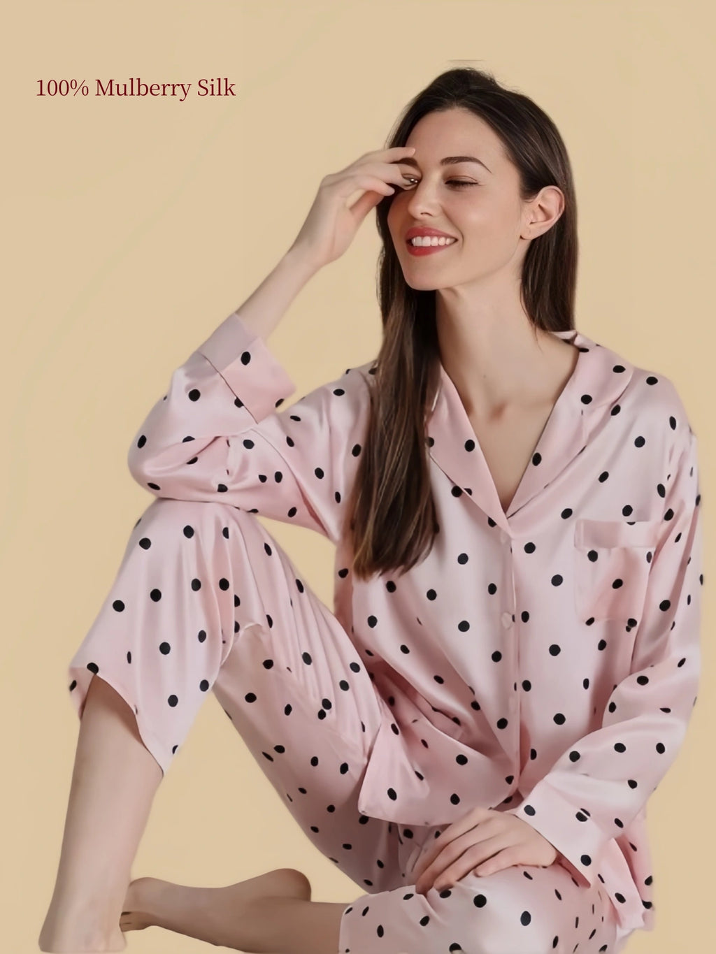Silkgala blush pink polka dot mulberry silk pajama set shown in a relaxed seated pose, highlighting the smooth fabric and flowing silhouette.