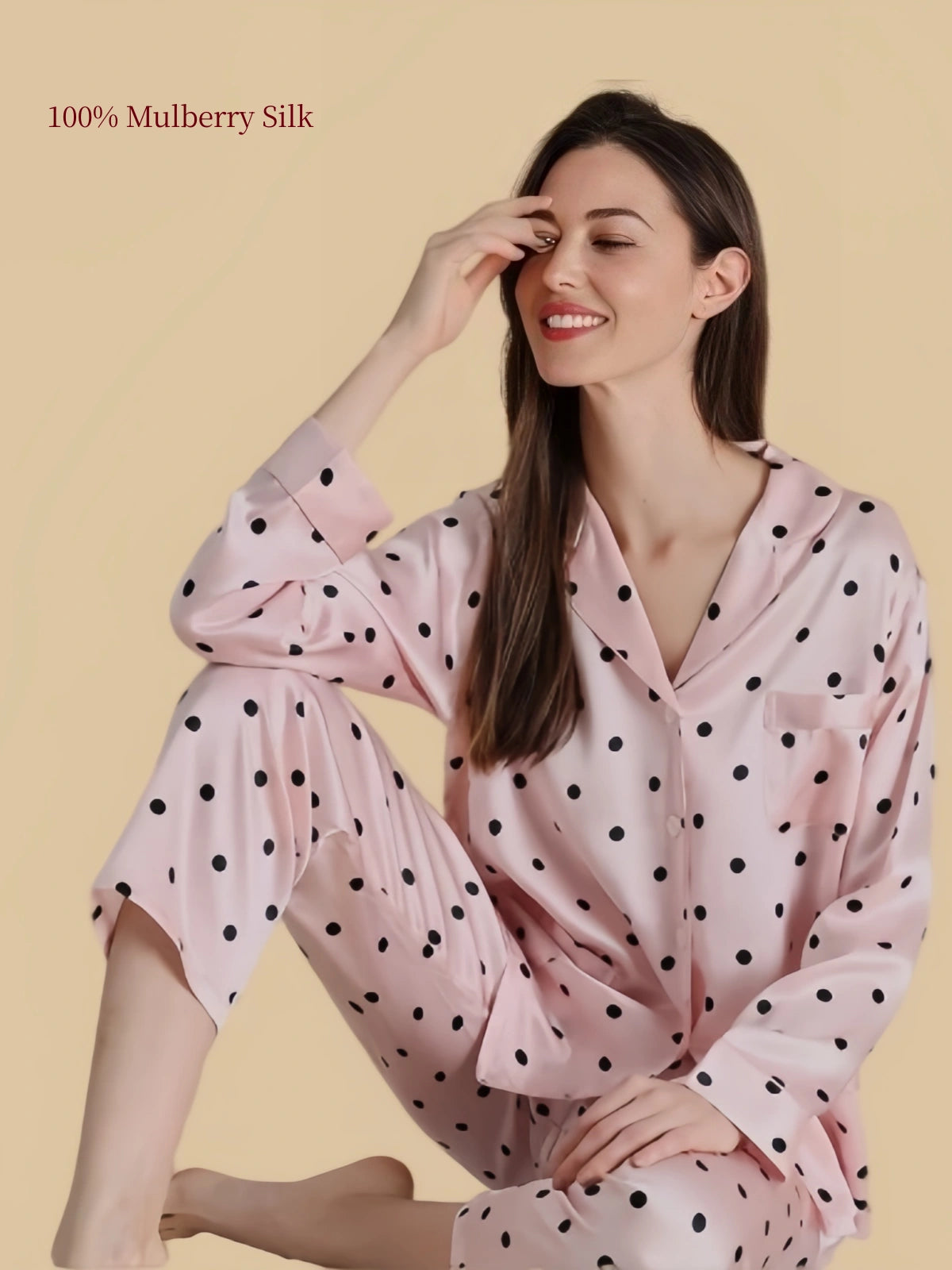 Silkgala blush pink polka dot mulberry silk pajama set shown in a relaxed seated pose, highlighting the smooth fabric and flowing silhouette.
