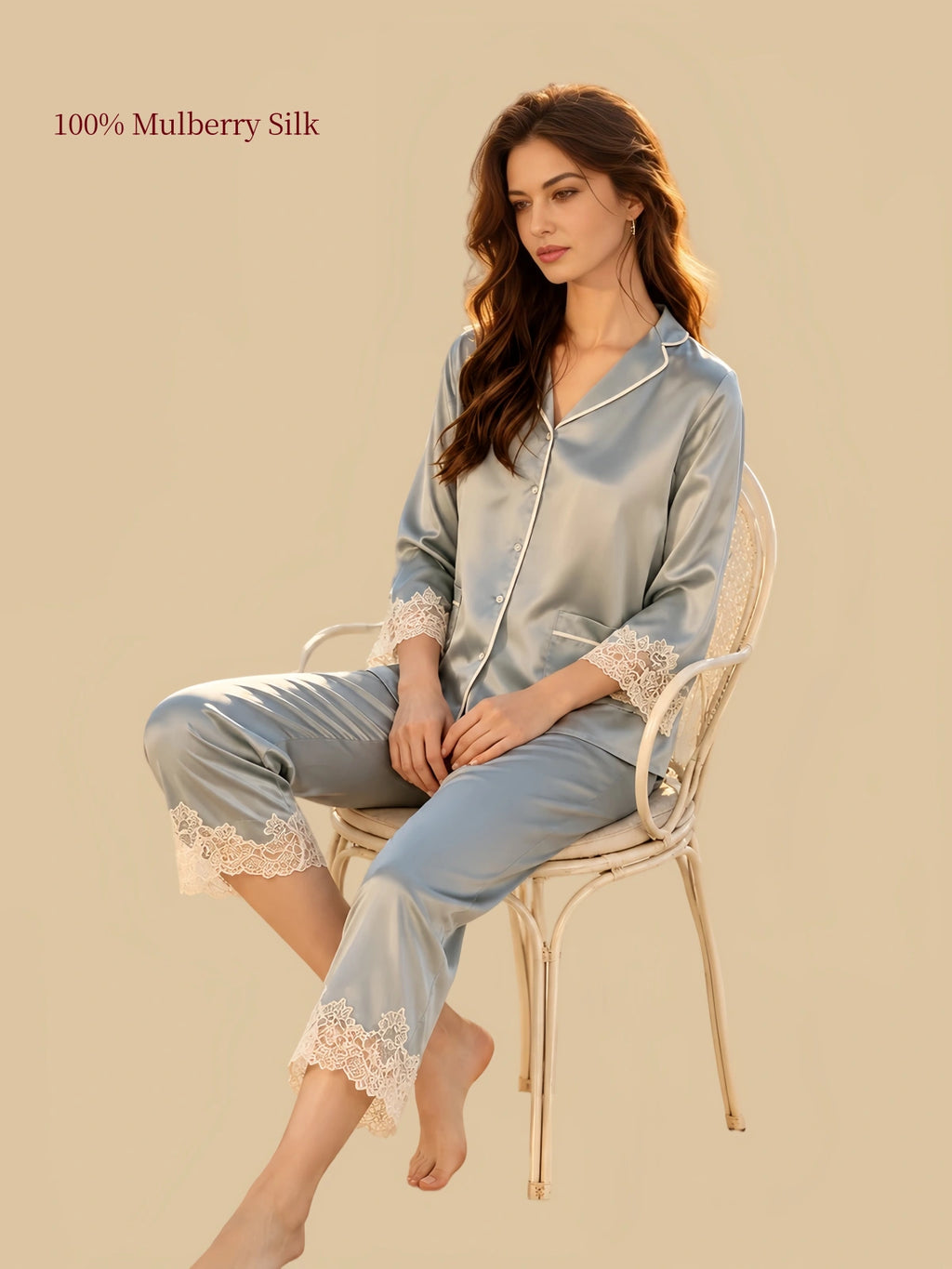 Model seated in Silkgala Green mulberry silk pajamas featuring three-quarter sleeves, delicate floral lace detailing and matching straight-leg pants.
