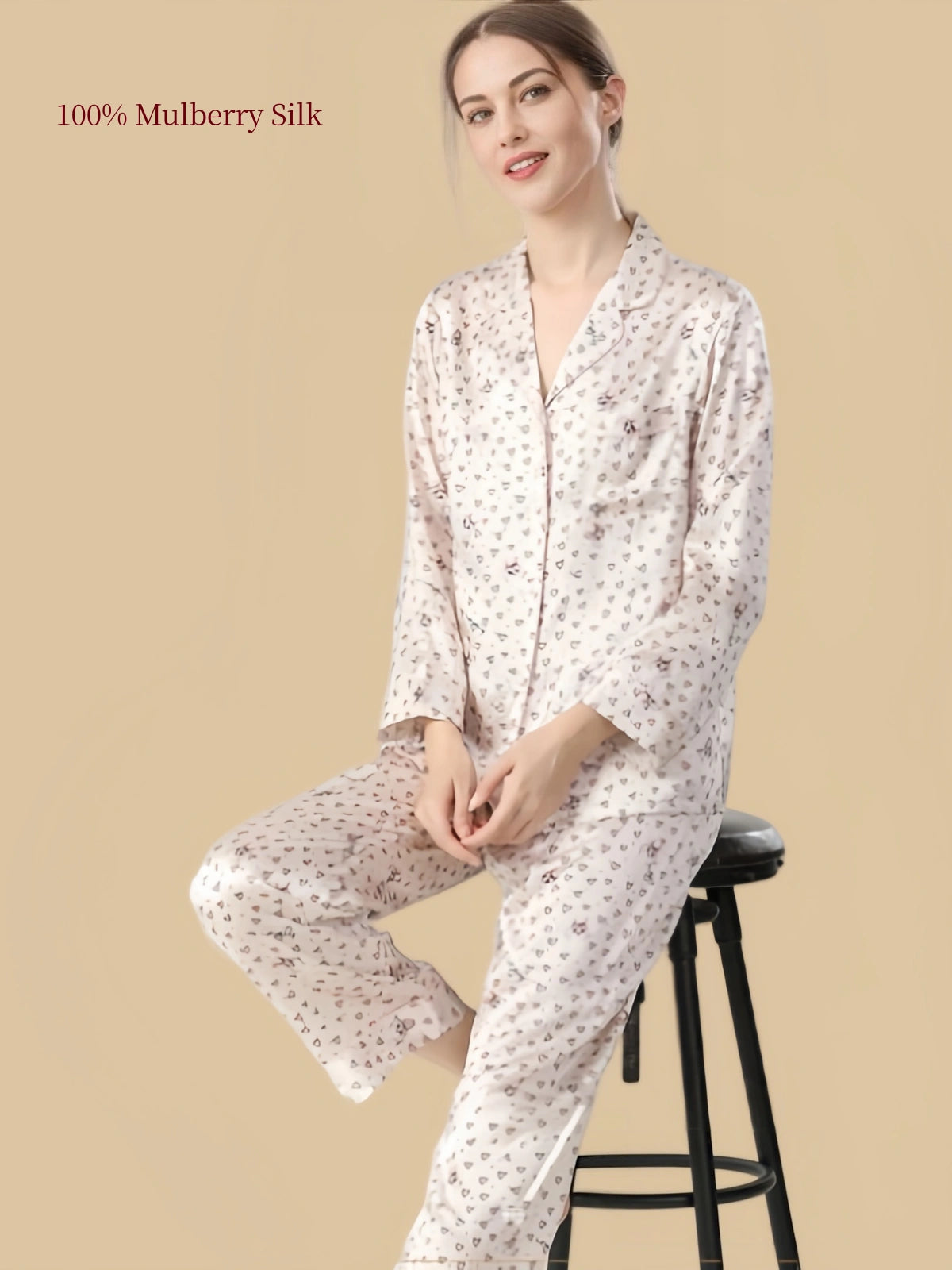 Seated model wearing Silkgala 19 Momme cat and heart print silk pajamas, showing the notched lapel collar, chest pocket and smooth silk drape.