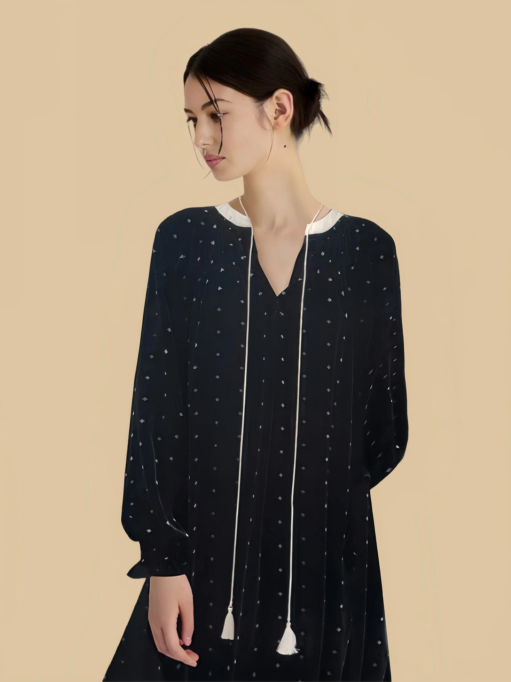 Black tassel-tie velvet dress close view with scattered star print and relaxed long-sleeve shape