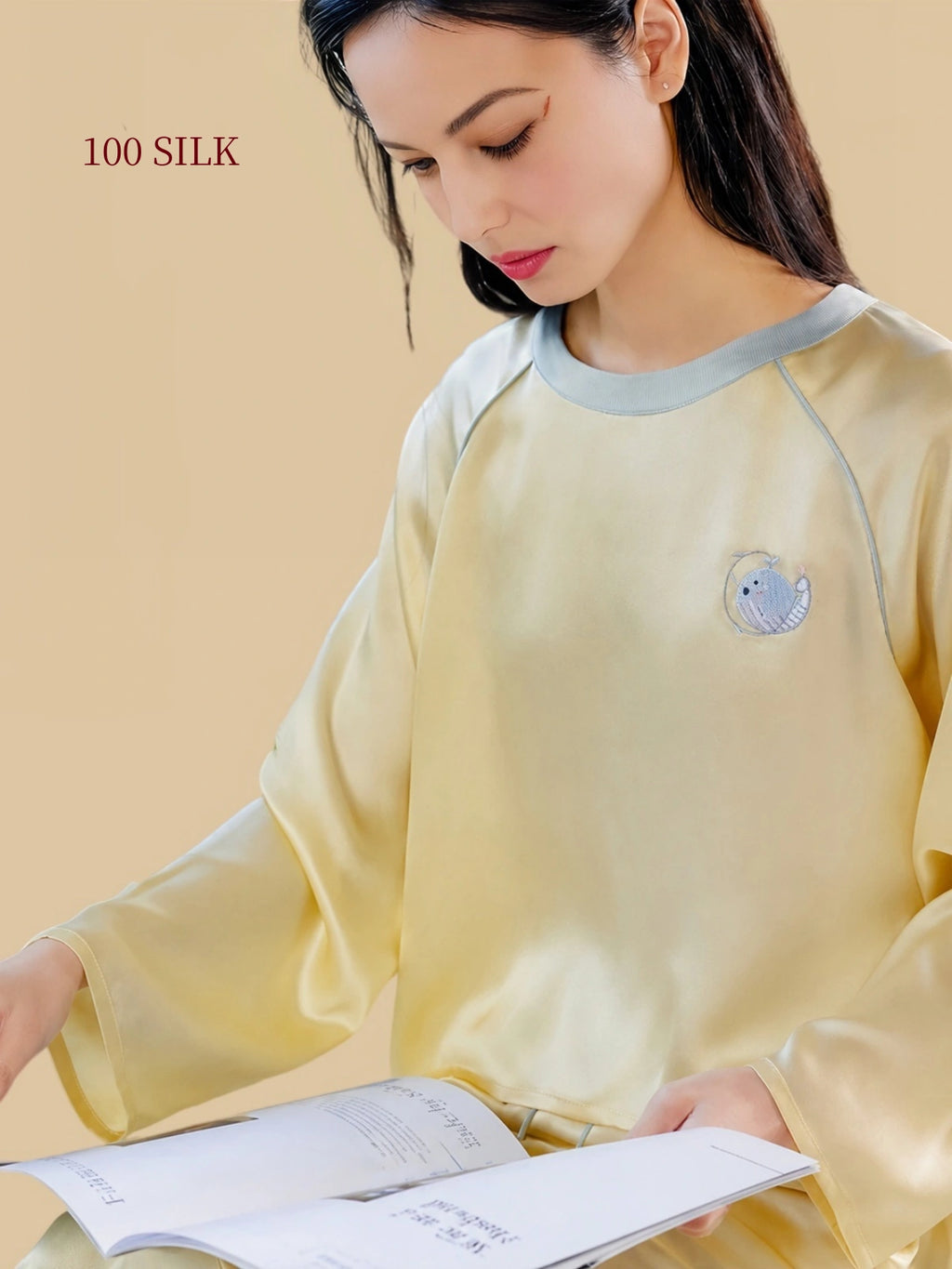 Close-up of Silkgala 22 momme silk pajama top featuring whale embroidery and a blue-gray contrast necklinee relaxed raglan pullover silhouette
