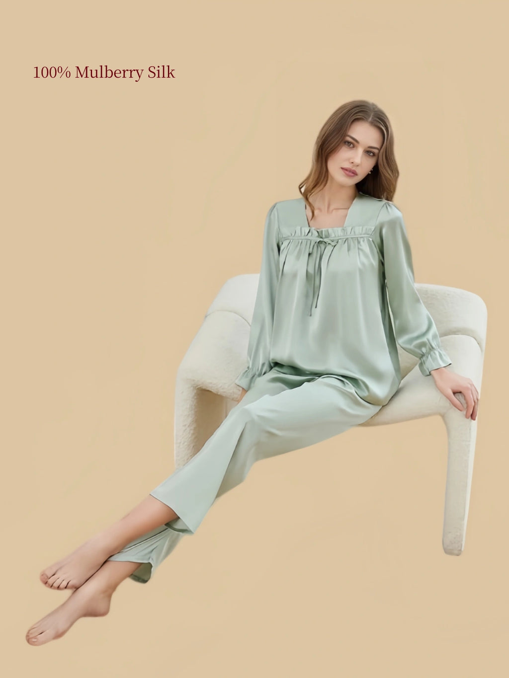 Model seated in Soft Sage Green Silkgala silk loungewear featuring a relaxed square-neck pullover top and straight-leg pants.