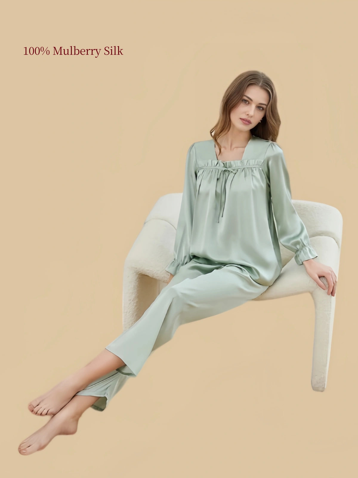 Model seated in Soft Sage Green Silkgala silk loungewear featuring a relaxed square-neck pullover top and straight-leg pants.